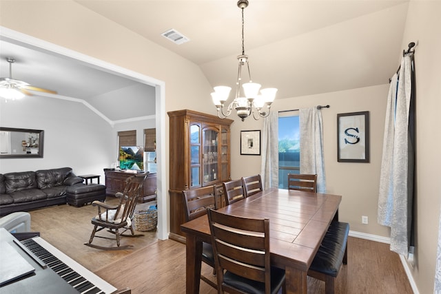 dining space with ceiling fan with notable chandelier, lofted ceiling, and light hardwood / wood-style floors