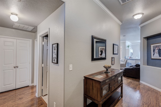 hallway featuring ornamental molding, wood-type flooring, and a textured ceiling