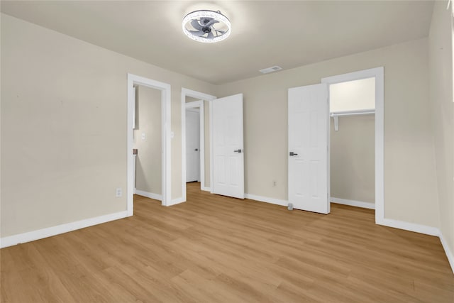 unfurnished bedroom with a closet, light hardwood / wood-style floors, and a walk in closet