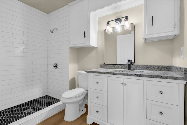 bathroom featuring tiled shower, vanity, toilet, and hardwood / wood-style flooring