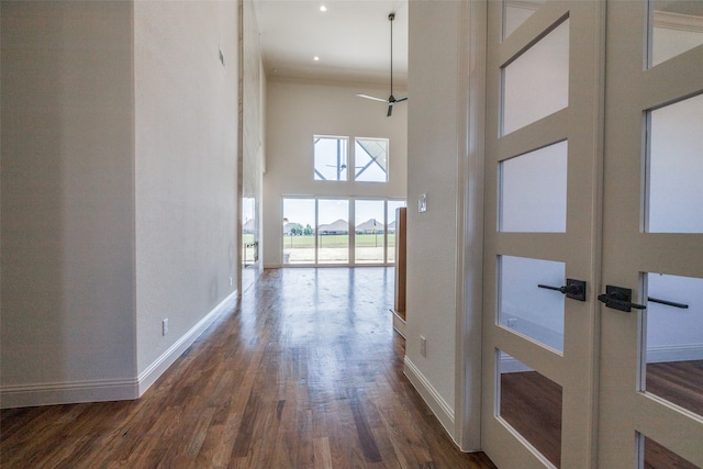 hall with french doors, dark hardwood / wood-style floors, a high ceiling, and crown molding