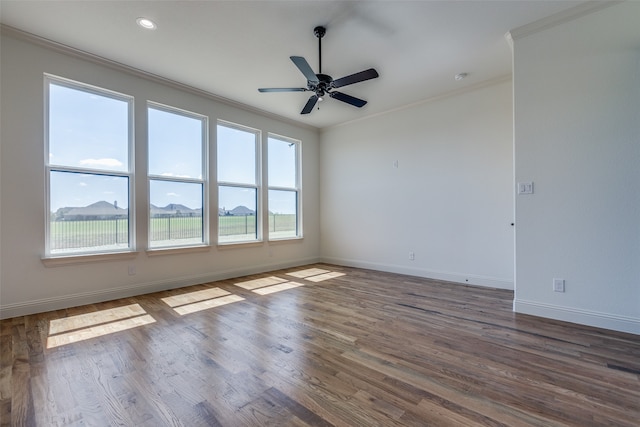 spare room featuring a healthy amount of sunlight, crown molding, dark wood-type flooring, and ceiling fan