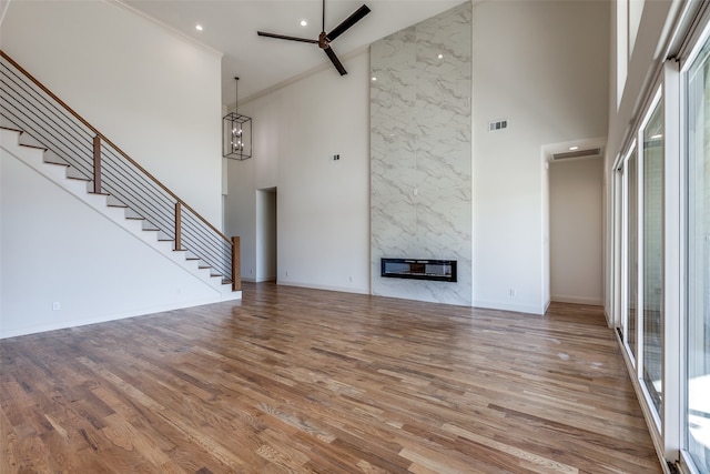 unfurnished living room with light hardwood / wood-style flooring, a high ceiling, and a fireplace