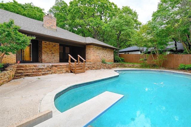 view of swimming pool featuring a patio and a diving board