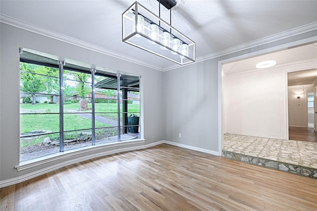 unfurnished room with an inviting chandelier, ornamental molding, and hardwood / wood-style floors