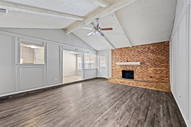 unfurnished living room featuring dark wood-type flooring, ceiling fan, a textured ceiling, and a brick fireplace