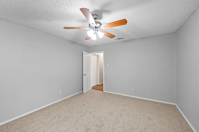 carpeted spare room featuring ceiling fan and a textured ceiling