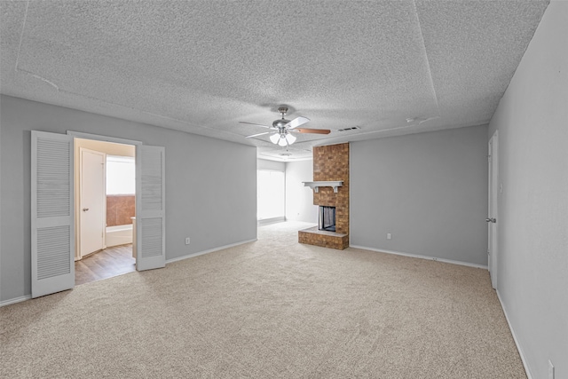 unfurnished living room with light carpet, a fireplace, a textured ceiling, and ceiling fan