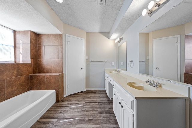 bathroom with vanity, a textured ceiling, wood-type flooring, and a washtub