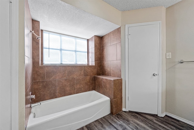 bathroom featuring a textured ceiling, tiled shower / bath combo, and hardwood / wood-style flooring