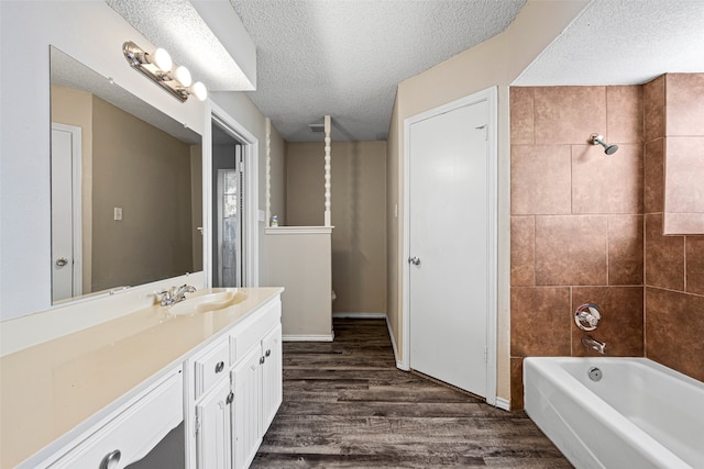 bathroom featuring vanity, a textured ceiling, tiled shower / bath, and hardwood / wood-style floors