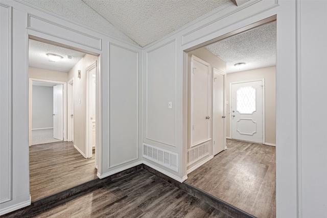 corridor featuring a textured ceiling and dark hardwood / wood-style flooring