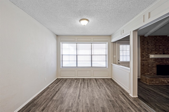 interior space featuring dark wood-type flooring, a textured ceiling, and a fireplace