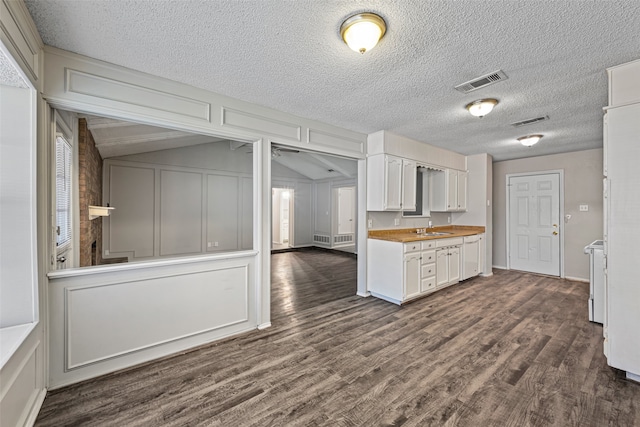 kitchen with sink, wood counters, a textured ceiling, white cabinetry, and dark hardwood / wood-style floors