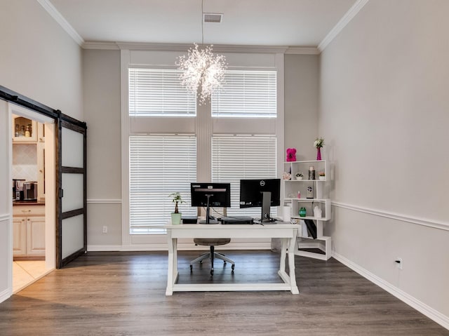 home office with a barn door, crown molding, and wood finished floors