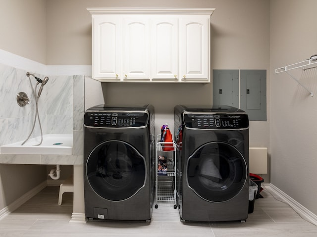 washroom featuring electric panel, washer and dryer, and cabinets