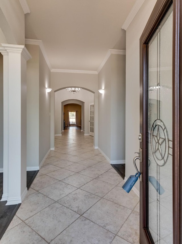 hallway featuring arched walkways, decorative columns, light tile patterned floors, ornamental molding, and baseboards