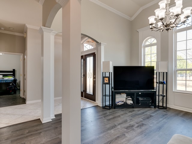 living room with ornate columns, ornamental molding, hardwood / wood-style flooring, an inviting chandelier, and vaulted ceiling