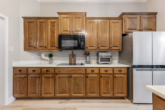 kitchen with light wood-type flooring, ornamental molding, and black appliances