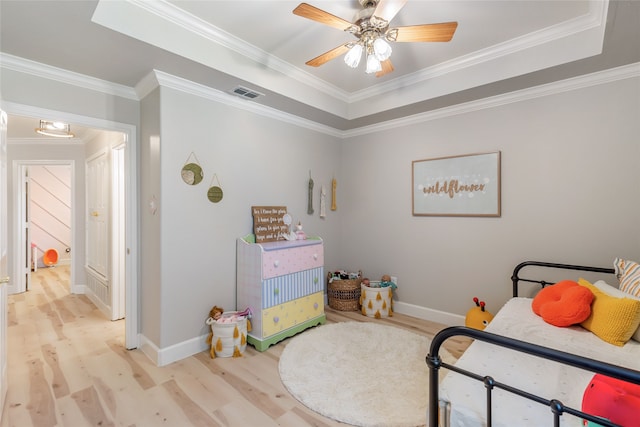 bedroom featuring light wood-type flooring, ceiling fan, a raised ceiling, and crown molding