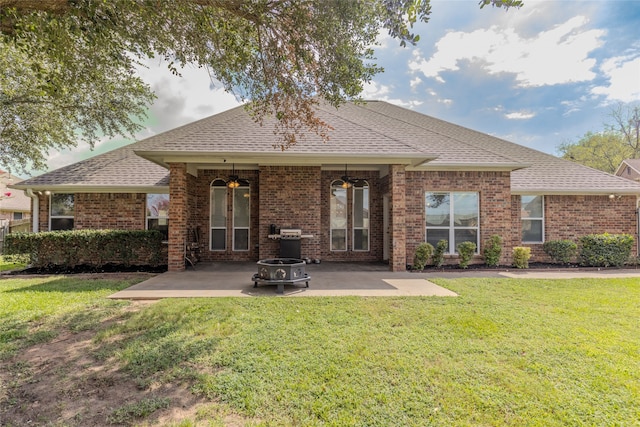 back of property featuring a lawn, ceiling fan, a patio area, and an outdoor fire pit