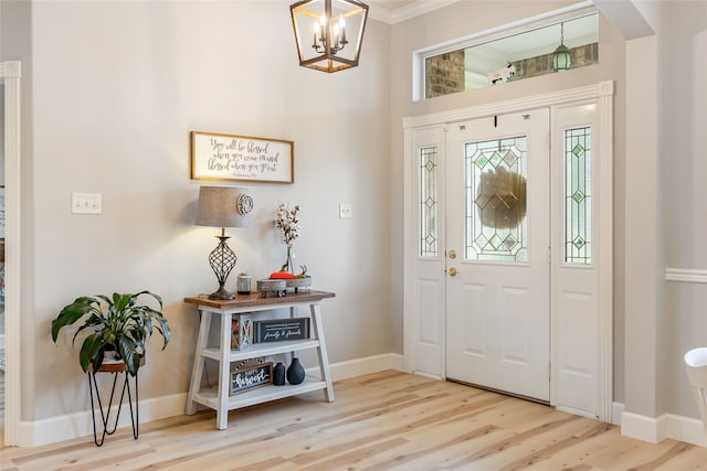 foyer with a chandelier, hardwood / wood-style floors, and crown molding