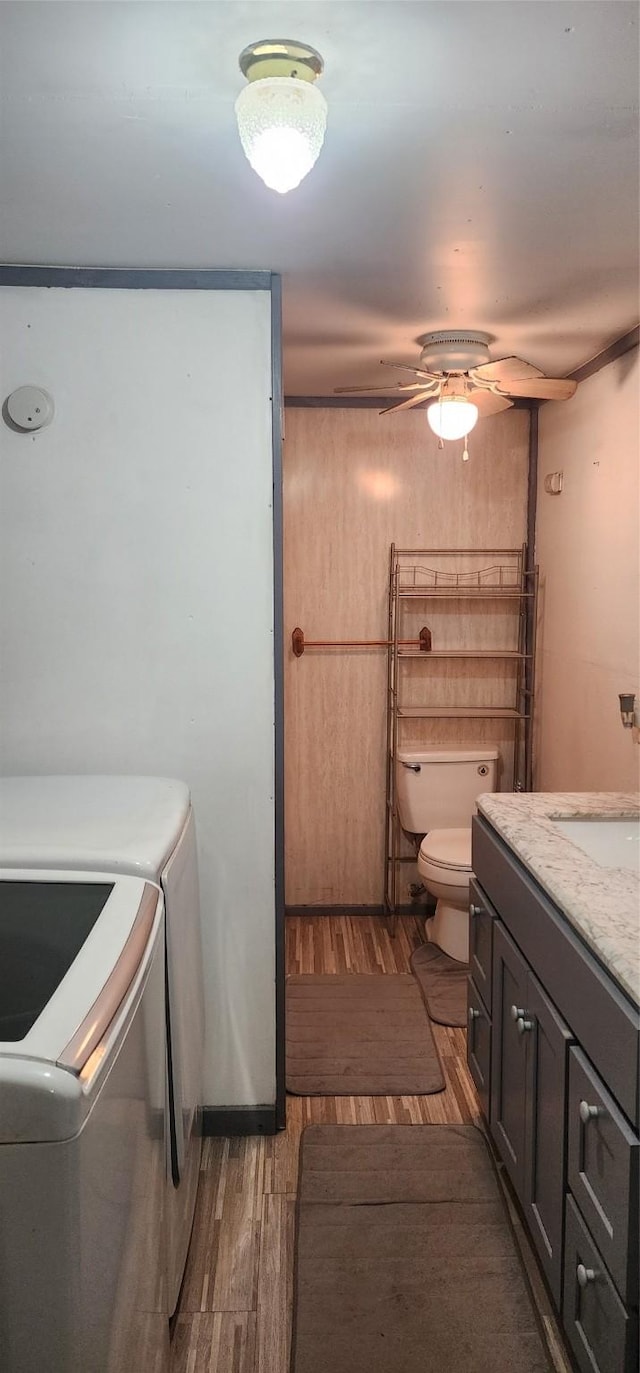 bathroom featuring vanity, hardwood / wood-style flooring, ceiling fan, toilet, and independent washer and dryer