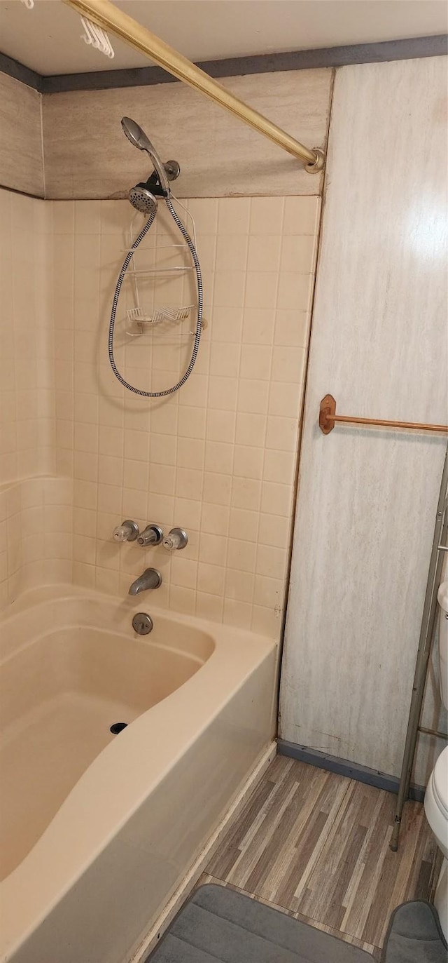 bathroom with hardwood / wood-style floors, tiled shower / bath combo, and toilet