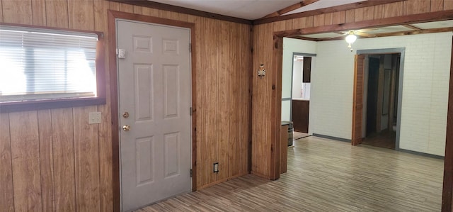 entryway featuring lofted ceiling, wooden walls, and light hardwood / wood-style flooring