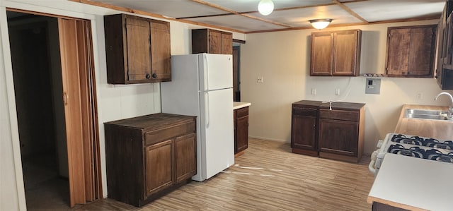 kitchen with light wood-type flooring, white appliances, sink, and dark brown cabinetry