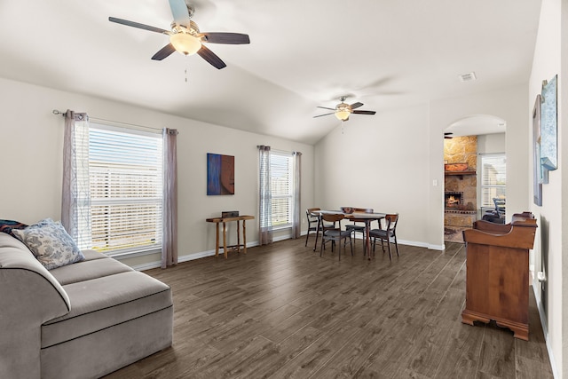 living room with vaulted ceiling, ceiling fan, a fireplace, and dark hardwood / wood-style flooring