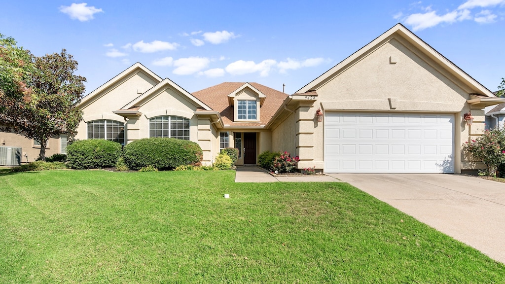 view of front of home featuring a garage, a front lawn, and central AC