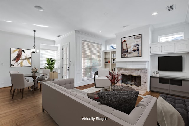 living room with ornamental molding, a high end fireplace, and light hardwood / wood-style flooring