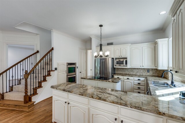 unfurnished living room with sink, a chandelier, light hardwood / wood-style floors, crown molding, and french doors