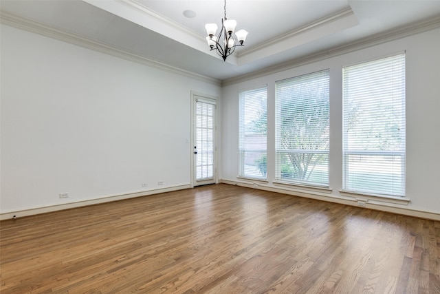 unfurnished room with crown molding, hardwood / wood-style floors, an inviting chandelier, and a tray ceiling