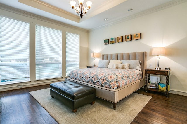 bedroom with an inviting chandelier, a tray ceiling, dark wood-type flooring, and ornamental molding