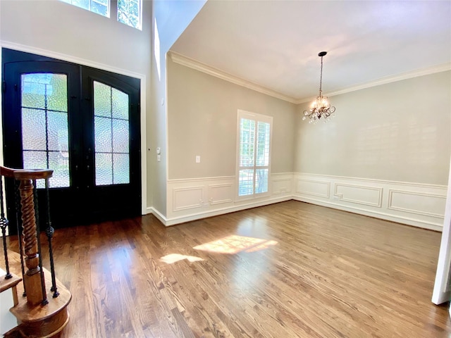 foyer with crown molding, a notable chandelier, hardwood / wood-style flooring, and french doors