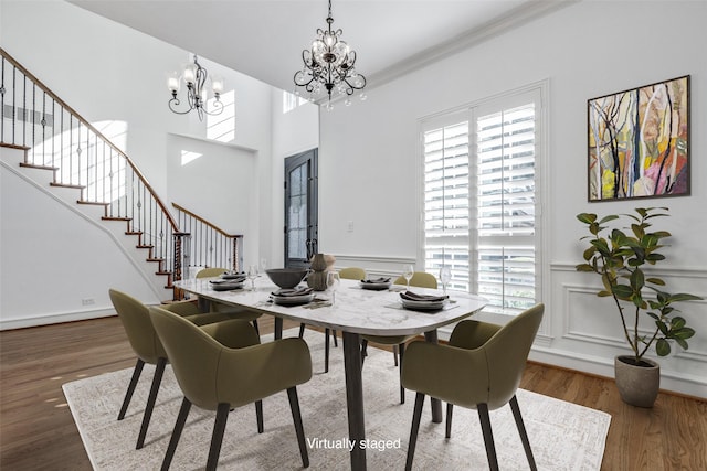 dining space featuring an inviting chandelier, crown molding, dark wood-type flooring, and a towering ceiling