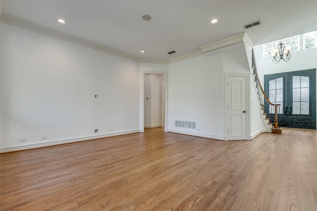 unfurnished living room with ornamental molding, light hardwood / wood-style flooring, a notable chandelier, and french doors