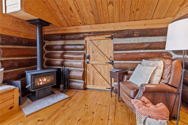 unfurnished room with log walls, light wood-type flooring, a wood stove, and wood ceiling