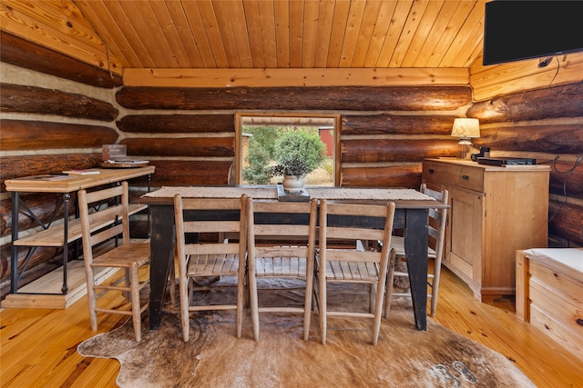 dining room with rustic walls, light hardwood / wood-style flooring, wood ceiling, and lofted ceiling