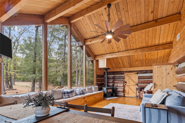 interior space featuring a wood stove, a wealth of natural light, ceiling fan, and wood-type flooring