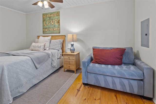 bedroom featuring hardwood / wood-style floors, electric panel, ceiling fan, and ornamental molding