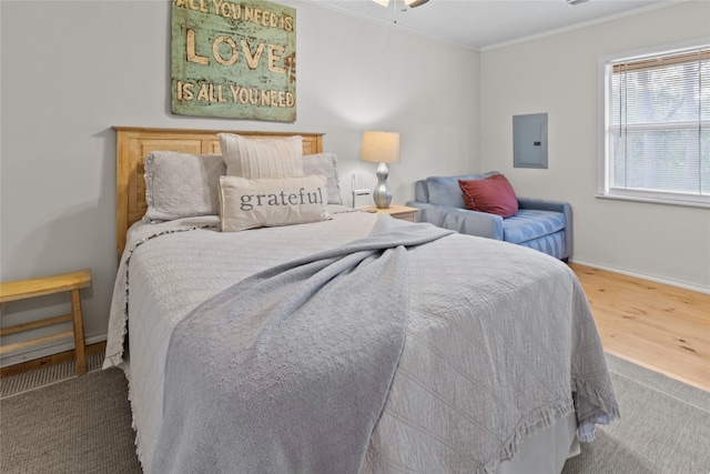 bedroom featuring electric panel, wood-type flooring, and ornamental molding