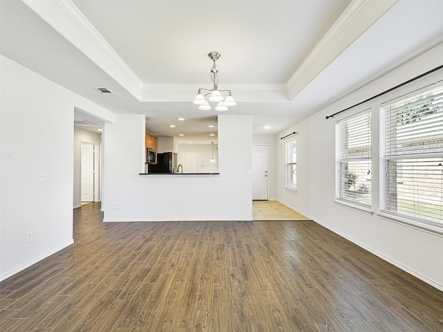 unfurnished living room with hardwood / wood-style flooring, a tray ceiling, and crown molding