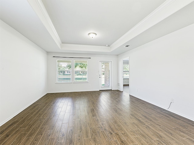 empty room featuring a tray ceiling, crown molding, a wealth of natural light, and dark wood-type flooring