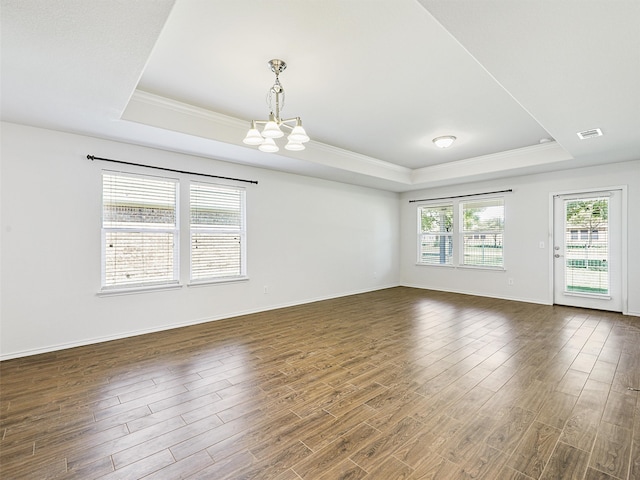 empty room with a raised ceiling, dark wood-type flooring, and a chandelier