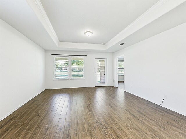 empty room with dark hardwood / wood-style flooring, a tray ceiling, and a healthy amount of sunlight