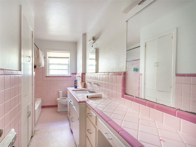 full bathroom featuring toilet, tub / shower combination, vanity, tile walls, and a textured ceiling