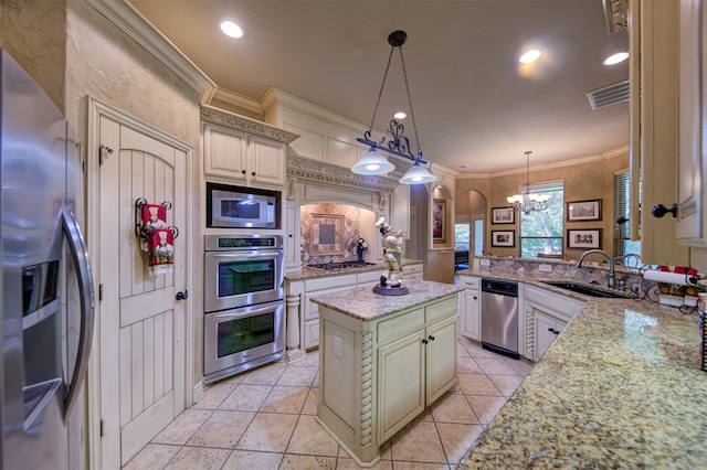 kitchen featuring a kitchen island, light stone countertops, stainless steel appliances, and decorative light fixtures